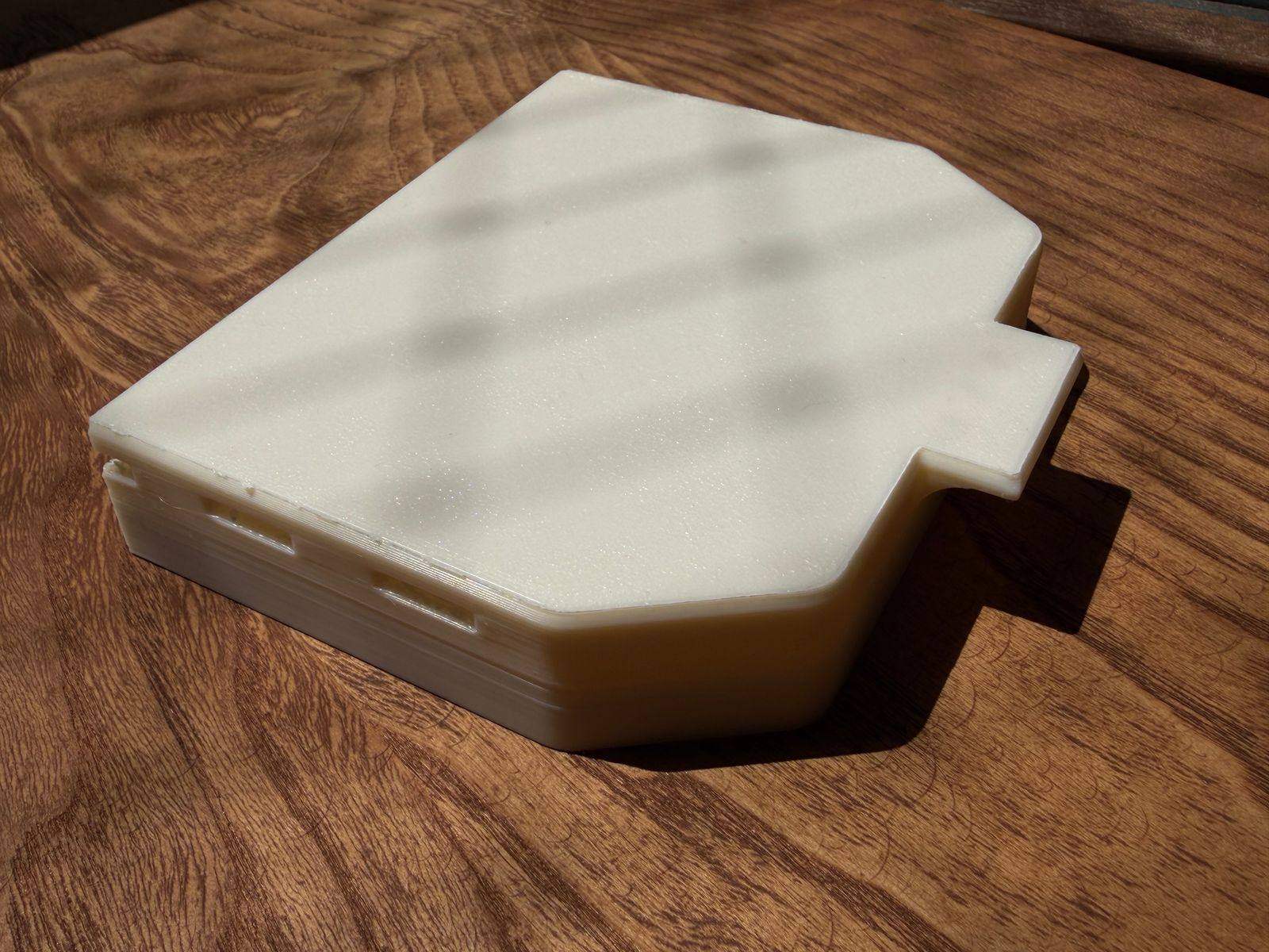 The 3D-printed white ASA shell of the dash cover seen from above, showing the moulded pull tab on one edge.