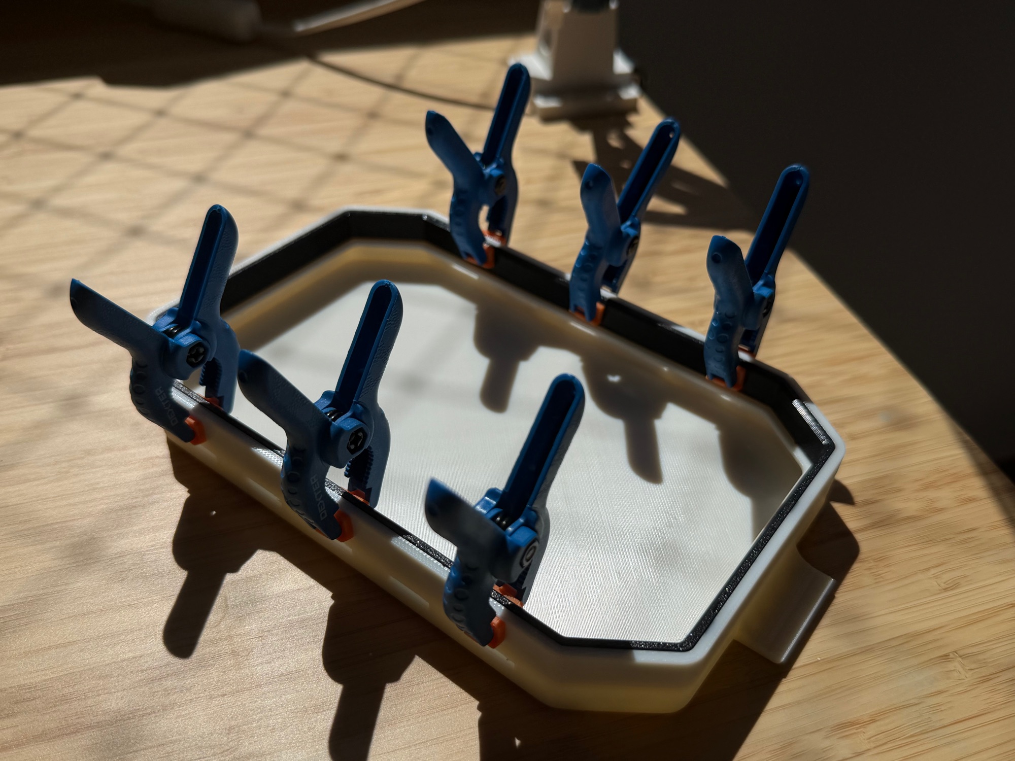 The TPU seal being glued into the ASA shell under seven blue spring clamps while the adhesive cures.
