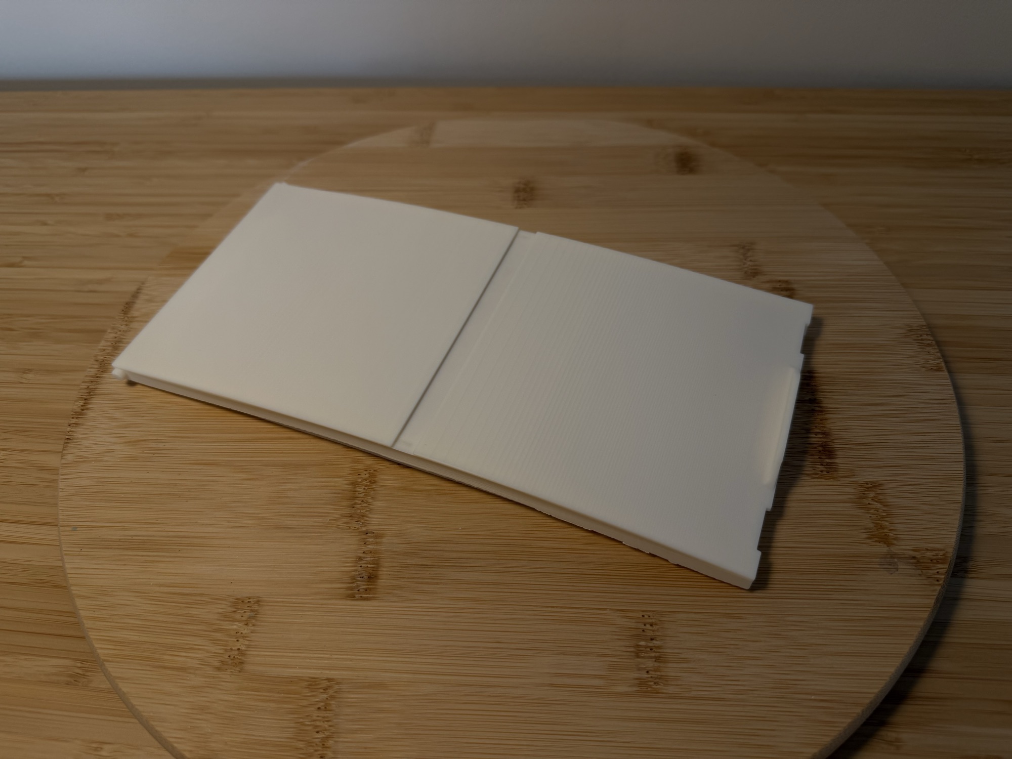 The new white lid on a wooden board, showing the joint between its two halves.